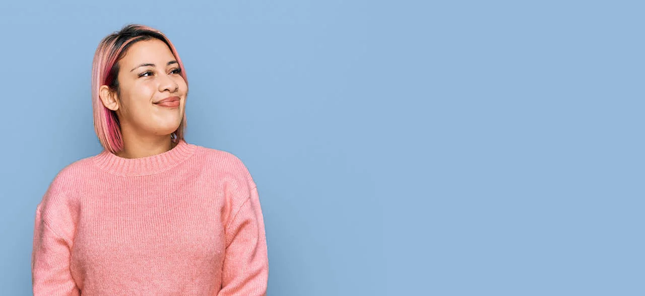 eine lächelnde Frau mit rosa Haaren und einem rosa Pullover