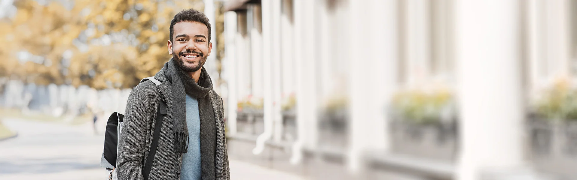 Ein junger Hochschulabsolvent verlässt die Uni und blickt dank Coaching für Akademiker positiv seiner beruflichen Zukunft entgegen.