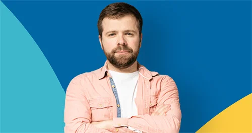 ein Mann mit gekreuzten Armen, der vor einem blauen und gelben Hintergrund steht