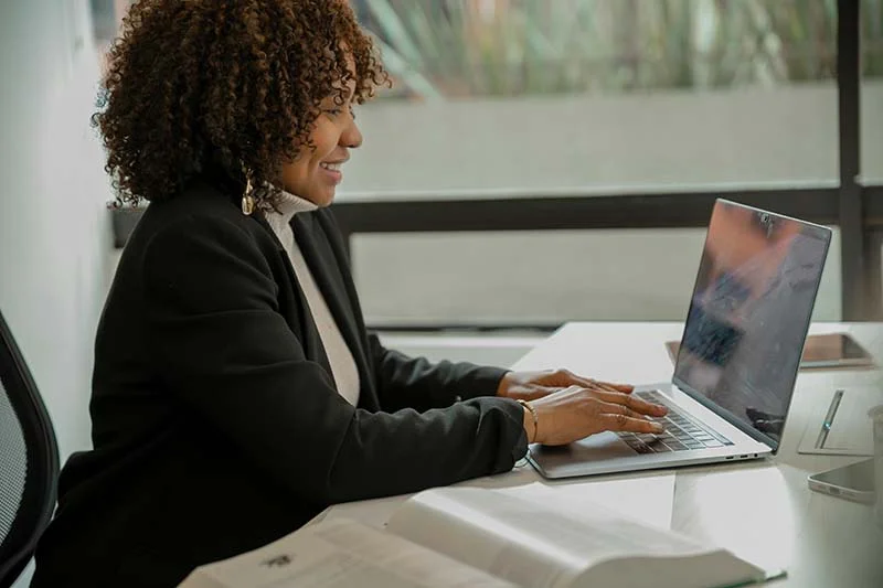 Frau mit Locken sitzt vor dem Laptop und lernt.