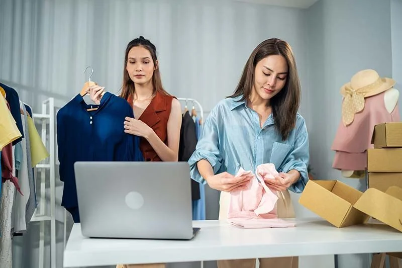 Zwei Einzelhandelskauffrauen kontrollieren und sortieren die neue Modekollektion.