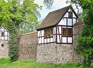 eine Steinmauer und darauf ein kleines weißes Haus